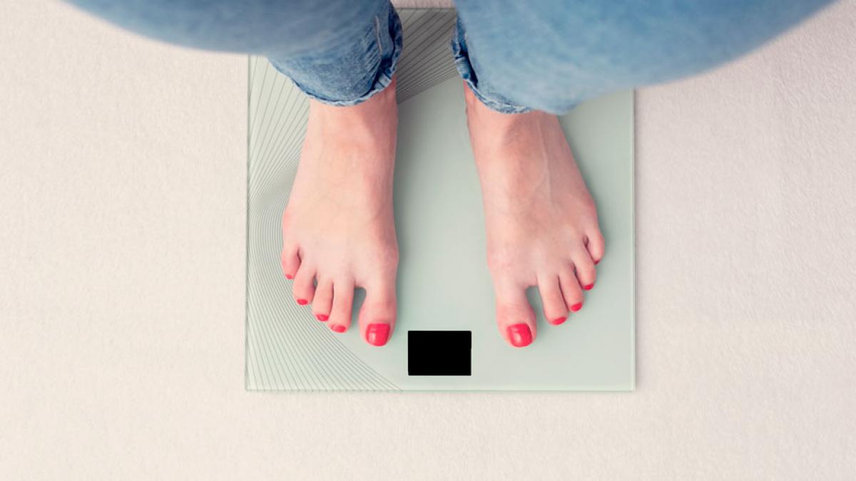 Pies femeninos en la balanza con la medida del peso corporal